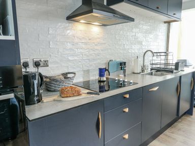 A kitchen with a countertop, stove, and sink at 7 Bro Branwen near Rhosneigr