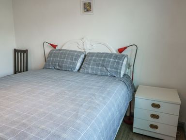A bedroom with a bed, nightstand, and lamp at 7 Bro Branwen Aberffraw near Rhosneigr