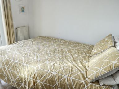 A bedroom with a bed covered in patterned bedding at 7 Bro Branwen Aberffraw near Rhosneigr