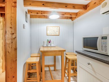 A small dining area with a wooden table and four stools under exposed wooden beams at Tryfan Cottage in Rhostryfan near Caernarfon
