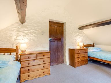 A bedroom with two single wooden beds two wooden dressers with lamps and a wooden door at Tryfan Cottage in Rhostryfan near Caernarfon