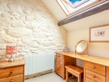 A room with a wooden desk and stool next to a stone wall and skylight at Tryfan Cottage in Rhostryfan near Caernarfon