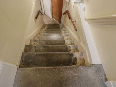 Stairs with a handrail leading to a door at Dollar Ward House Basement Cirencester