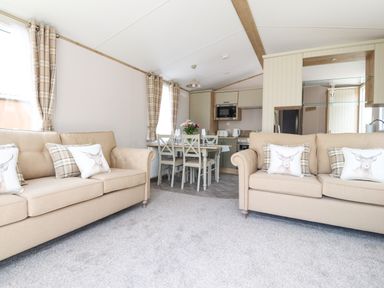 A living area with two beige sofas and a dining table with chairs and a kitchen in the background at 25 Sherwood South Lakeland Leisure Village