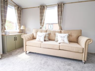 A beige sofa with patterned and animal print cushions in a room with carpet and green cabinet at 25 Sherwood South Lakeland Leisure Village