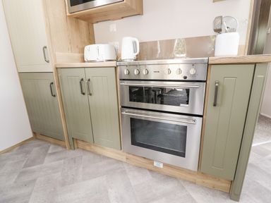 A kitchen with olive green cabinets a stainless steel oven a white toaster and kettle at 25 Sherwood South Lakeland Leisure Village