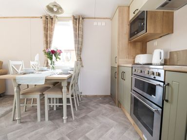 A kitchen with dining table set with plates and glasses next to oven microwave and toaster at 25 Sherwood South Lakeland Leisure Village