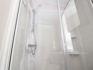 A shower area with a handheld showerhead and glass doors at 25 Sherwood in South Lakeland Leisure Village