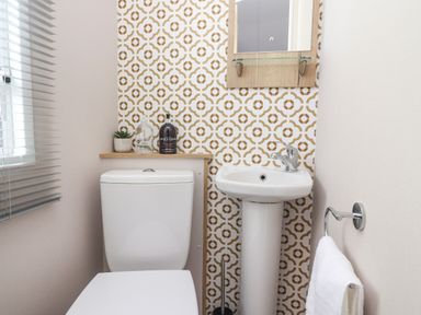 A bathroom with a toilet sink towel and patterned wallpaper at 25 Sherwood in South Lakeland Leisure Village