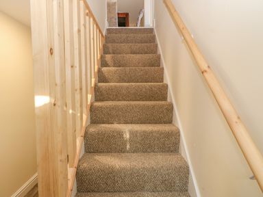 A carpeted staircase with wooden handrails on both sides at The Apartment at Plas Yr Eithin in Amlwch near Llanfechell