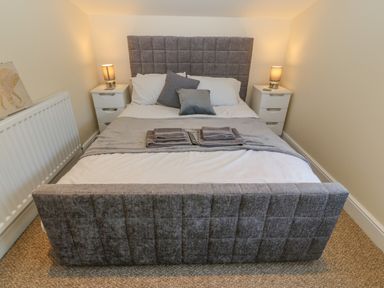 A bedroom with a double bed two bedside tables with lamps and folded towels on the bed at The Apartment at Plas Yr Eithin Amlwch near Llanfechell