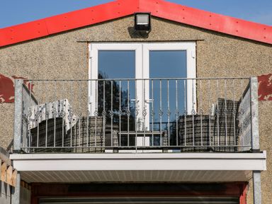 A balcony with outdoor furniture and a blanket on a chair at The Apartment at Plas Yr Eithin in Amlwch near Llanfechell