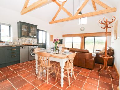 A kitchen and dining area with wooden beams and tiled floor at Little Barn in Tittleshall