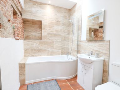 A bathroom with a bathtub shower combination sink cabinet and toilet at Little Barn in Tittleshall
