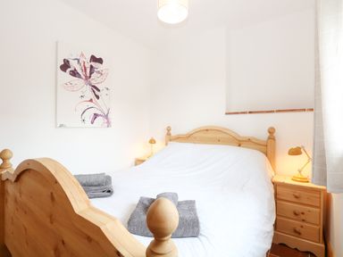A bedroom with a wooden bed and two matching bedside tables with lamps at Little Barn Tittleshall