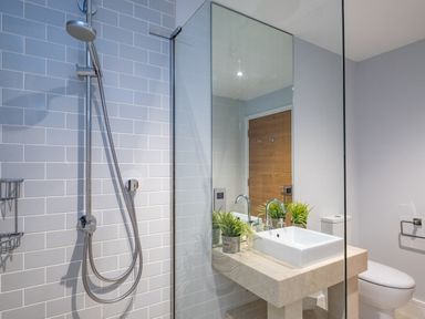 A bathroom with a shower area a sink with faucet a toilet and a mirror at Seascape in Polzeath