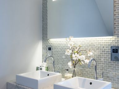 A bathroom with two sinks a vase with flowers and a mirror at Seascape in Polzeath
