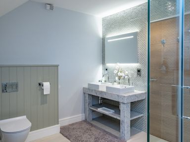 A bathroom with a double sink vanity a large mirror a toilet and a glass shower at Seascape in Polzeath