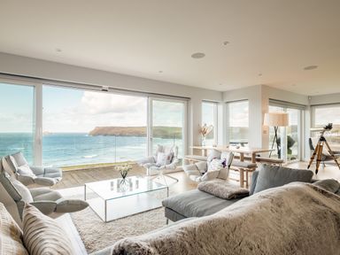 A living room with chairs a glass coffee table a dining table a floor lamp and a telescope with an ocean view at Seascape in Polzeath