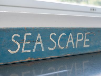 A close-up of a blue wooden sign with the word seascape painted in white
