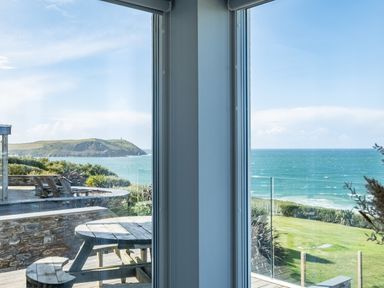 A coastal view with a wooden picnic table and chairs on a deck overlooking the sea at Seascape in Polzeath