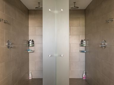 A double shower with frosted glass divider and shampoo bottles on shelves at Seascape in Polzeath