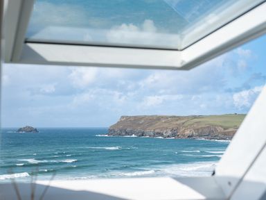 View of the ocean and coastline through an open window at Seascape in Polzeath