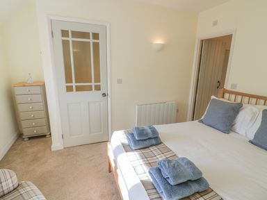 A bedroom with a bed with blue towels and pillows a chest of drawers and two doors at Bumble Cottage in Tysoe