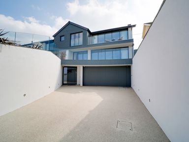 A driveway leading to a modern house with large windows and a garage at Megizzy in Polzeath