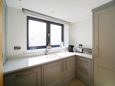 A kitchen with a sink toaster coffee maker and cabinets at Megizzy in Polzeath