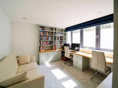 A home office with a beige sofa bookshelves two chairs a computer and a printer by windows at Megizzy in Polzeath