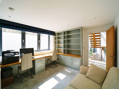 A home office with built in shelves desk with computer printer two chairs and a beige sofa at Megizzy in Polzeath