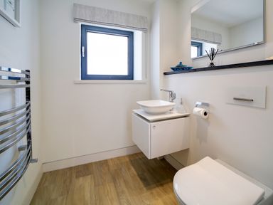 A bathroom with a wall-mounted sink and toilet a window and a towel rack at Megizzy in Polzeath