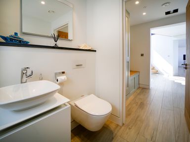 A bathroom with a wall-mounted toilet a sink with a faucet and a mirror above at Megizzy in Polzeath