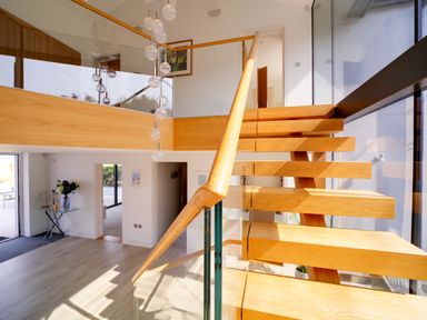 A wooden staircase with glass balustrades in a modern house interior at Megizzy Polzeath