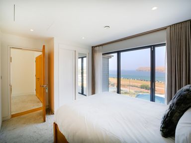 A bedroom with a large bed and a window with sea view at Megizzy in Polzeath