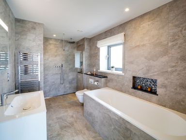 A bathroom with a bathtub sink shower window and heated towel rail at Megizzy in Polzeath
