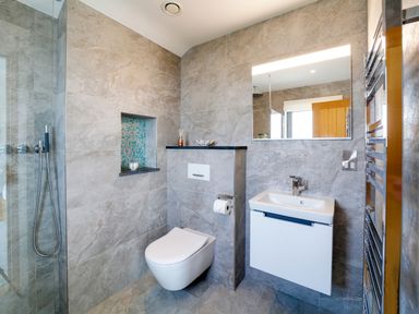 A bathroom with a wall-mounted toilet sink and mirror at Megizzy in Polzeath
