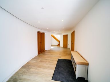 A hallway with wooden floor benches a carpet and wooden doors at Megizzy in Polzeath