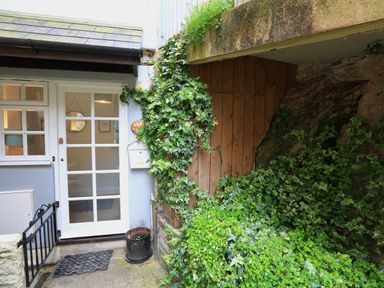 A white door with glass panels next to a plant-covered wooden wall outside a building at Ferry View in Dartmouth