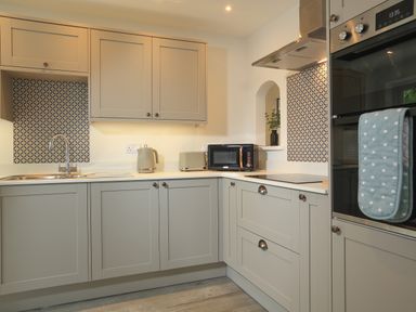 A kitchen with grey cabinets a sink kettle toaster microwave and oven at Ferry View Dartmouth