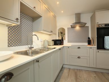 A kitchen with beige cabinets a double sink a microwave and a stovetop with a range hood at Ferry View in Dartmouth