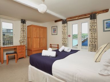 A bedroom with a bed rolled towels wooden wardrobe desk and chair near windows at Ferry View in Dartmouth