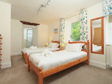 A bedroom with two single beds wooden frames bedside tables lamps and a wall mirror at Ferry View in Dartmouth