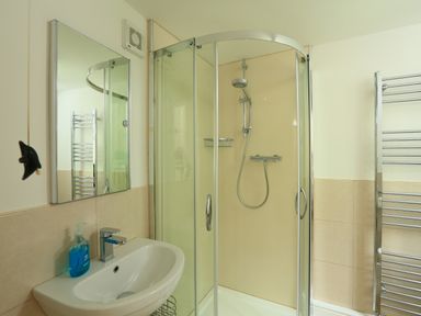 A bathroom with a sink a mirror a glass shower enclosure and a towel rack at Ferry View in Dartmouth