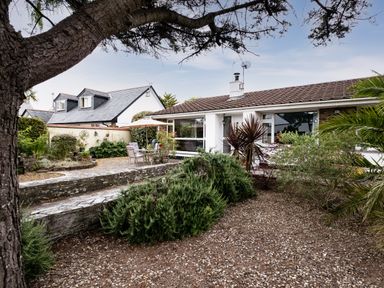 A garden with shrubs and patio furniture outside a bungalow at Longhouse Bungalow in Rock