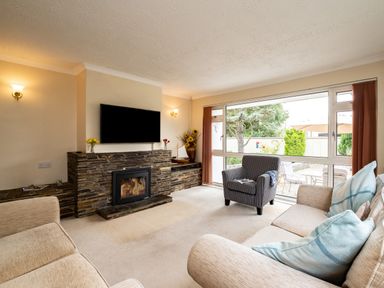 A living room with a stone fireplace television armchair sofa and large window at Longhouse Bungalow in Rock