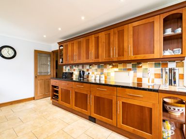 A kitchen with wooden cabinets tiled backsplash and countertop at Longhouse Bungalow in Rock