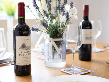 A dining table with a bottle of red wine a wine glass and a vase with flowers at Longhouse Bungalow Rock