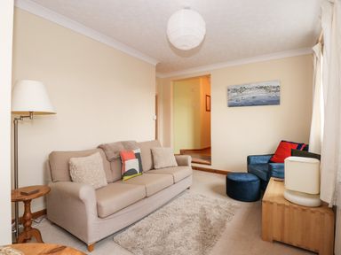 A living room with a beige sofa and a blue armchair with cushions at 16 Norfolk Heights in Docking
